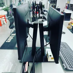 Zwei Computermonitore stehen nebeneinander auf einem Schreibtisch.