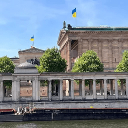 Ein großes Gebäude mit einer Flagge darauf steht neben einem Gewässer.