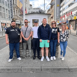Eine Gruppe von Menschen steht nebeneinander auf einem Bürgersteig vor einem Gebäude.