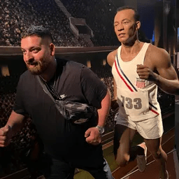 Ein Mann steht neben der Statue eines Mannes, der auf einer Laufstrecke läuft.