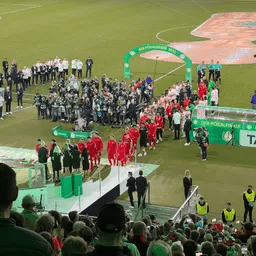 Eine Gruppe von Menschen steht auf einem Fußballfeld.