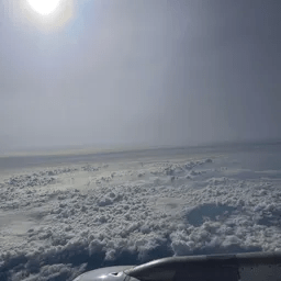 Ein Blick aus einem Flugzeugfenster auf einen bewölkten Himmel.