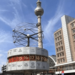Ein großer Uhrturm inmitten einer Stadt mit Gebäuden im Hintergrund.