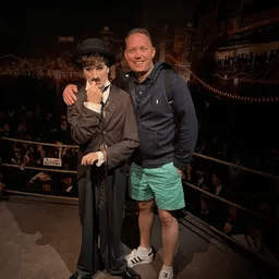 Ein Mann steht neben einer Wachsfigur von Charlie Chaplin.