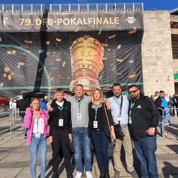 Eine Gruppe von Menschen posiert für ein Foto vor einer großen Trophäe.