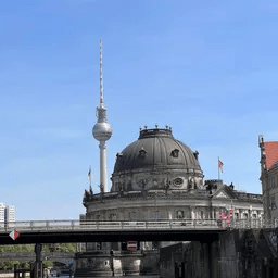 Eine Brücke über einen Fluss mit einer Kuppel und einem Turm im Hintergrund.