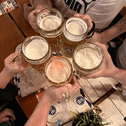 Eine Gruppe von Leuten stößt an einem Tisch mit Bierkrügen an.