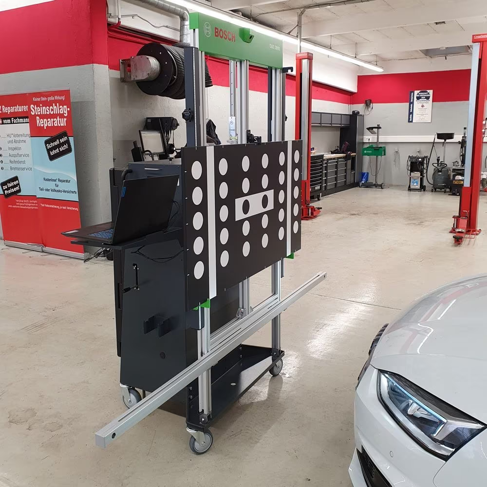 Ein weißes Auto steht neben einer Maschine in einer Garage