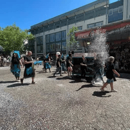 Eine Gruppe von Menschen geht eine Straße vor einem Gebäude entlang.
