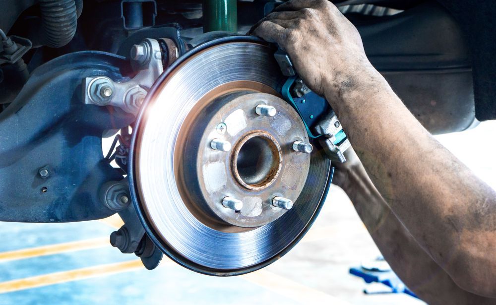 Bremsenservice Lörrach: Mechaniker prüft Bremsscheibe und Bremssattel an einem Fahrzeug
