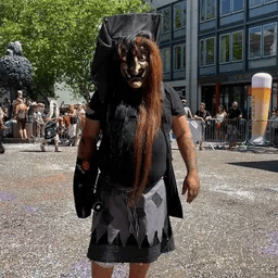 Ein Mann in einem Hexenkostüm steht vor einer Menschenmenge.