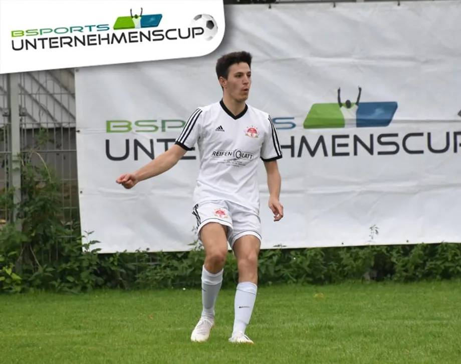 Ein Fußballspieler vor einem Banner mit der Aufschrift „UnternehmenCup“