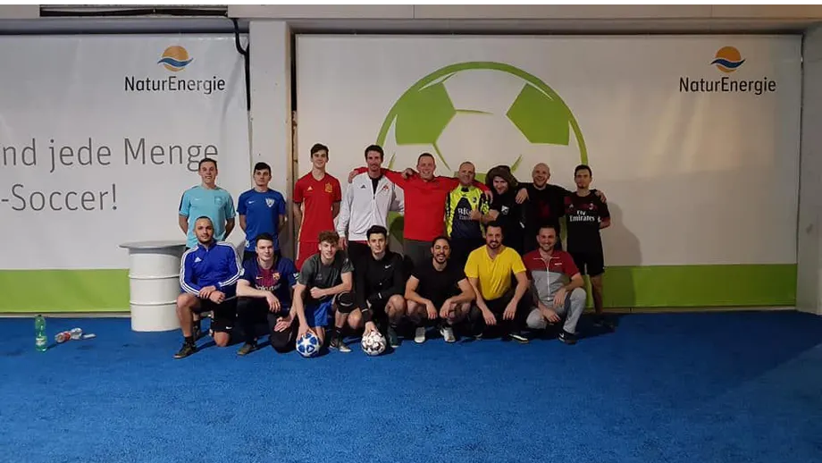 Eine Gruppe von Menschen posiert für ein Foto mit einem Fußball im Hintergrund