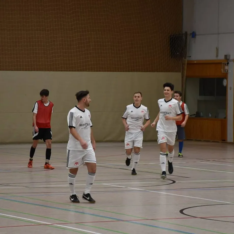 Eine Gruppe junger Männer spielt in einer Turnhalle Fußball.