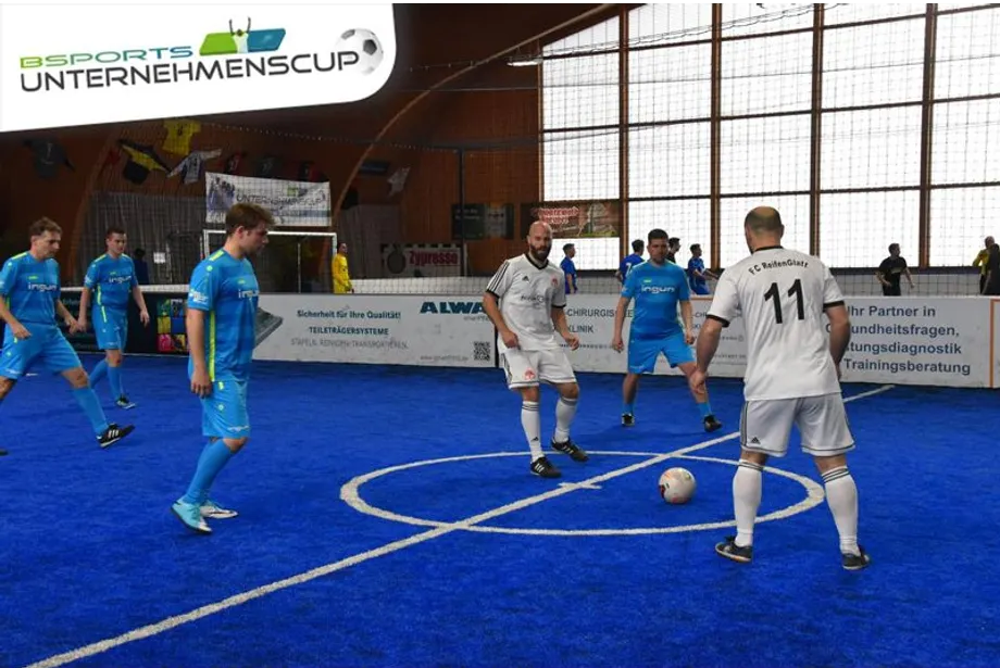 Eine Gruppe Männer spielt Fußball auf einem blauen Feld.