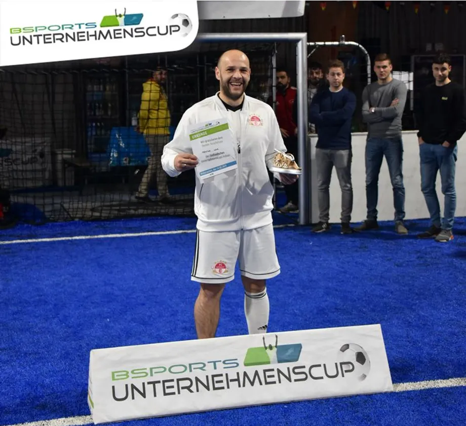Ein Mann steht vor einem Schild mit der Aufschrift „Sports Unternehmencup“