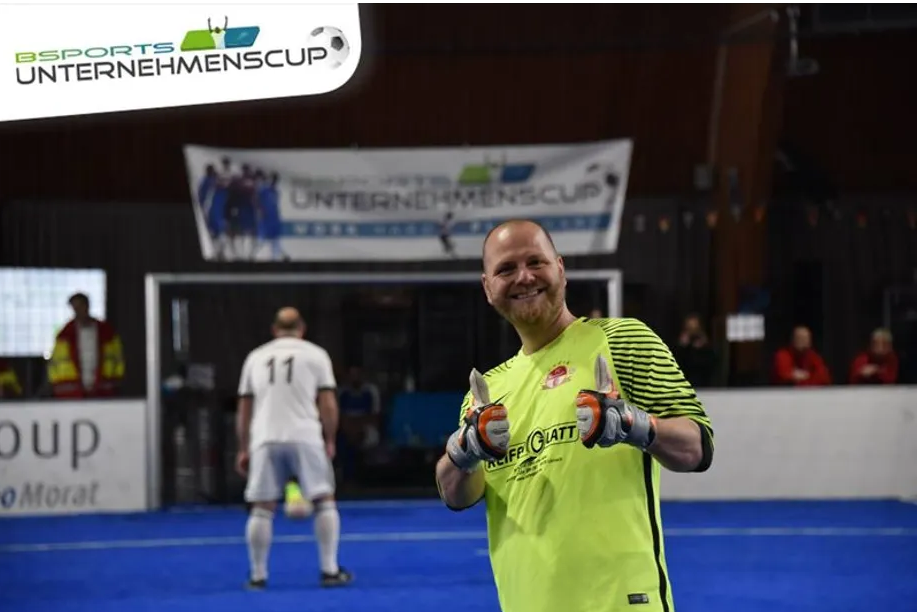 Ein Mann steht auf einem Fußballfeld und zeigt den Daumen nach oben.