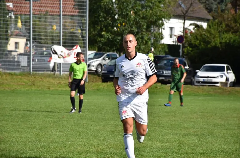 Ein Mann in einem weißen Trikot läuft auf einem Fußballfeld.