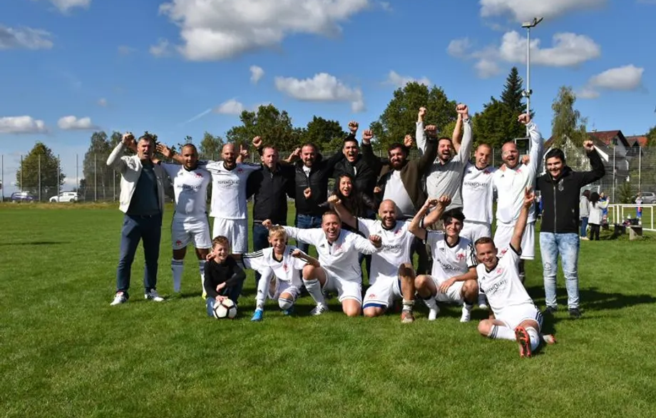 Eine Gruppe Fußballspieler posiert auf einem Feld für ein Foto.