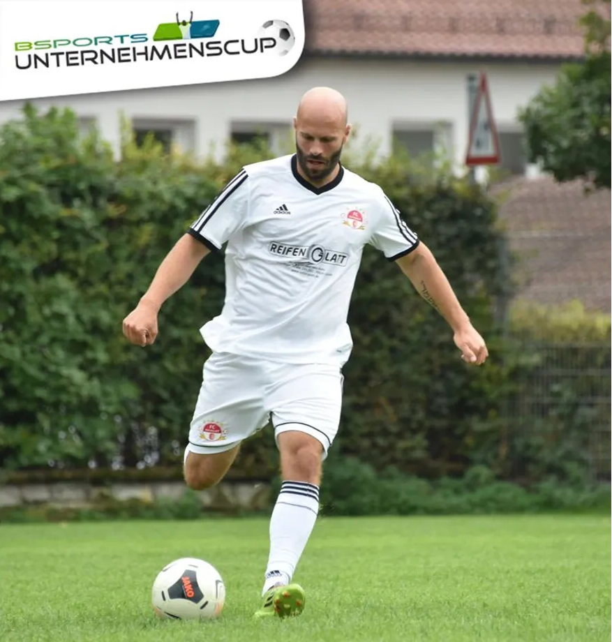 Ein Mann in einem weißen Hemd, der einen Fußball kickt