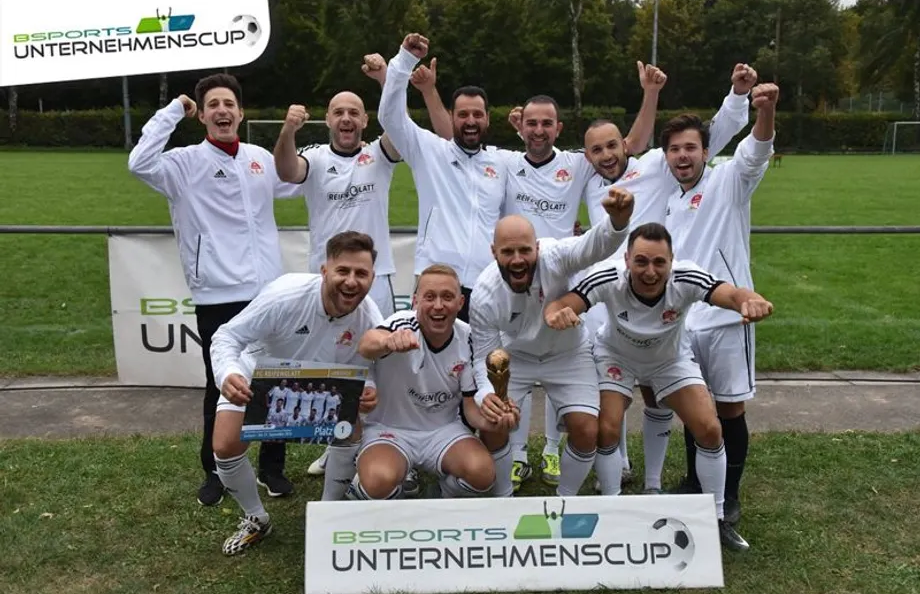 Eine Gruppe von Fußballspielern posiert für ein Foto vor einem Schild mit der Aufschrift „Unternehmencup“