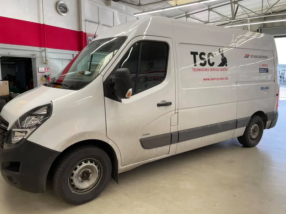 Ein weißer Lieferwagen mit der Aufschrift „TSC“ steht in einer Garage.