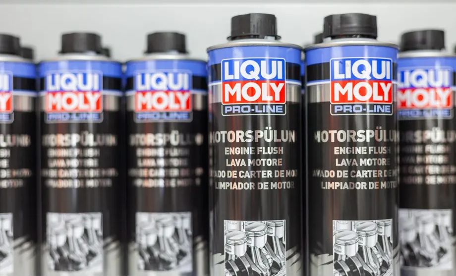 Eine Reihe von Motorreinigern von Liqui Moly steht aufgereiht auf einem Regal.