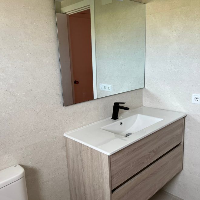 Un baño con lavabo, inodoro y espejo.