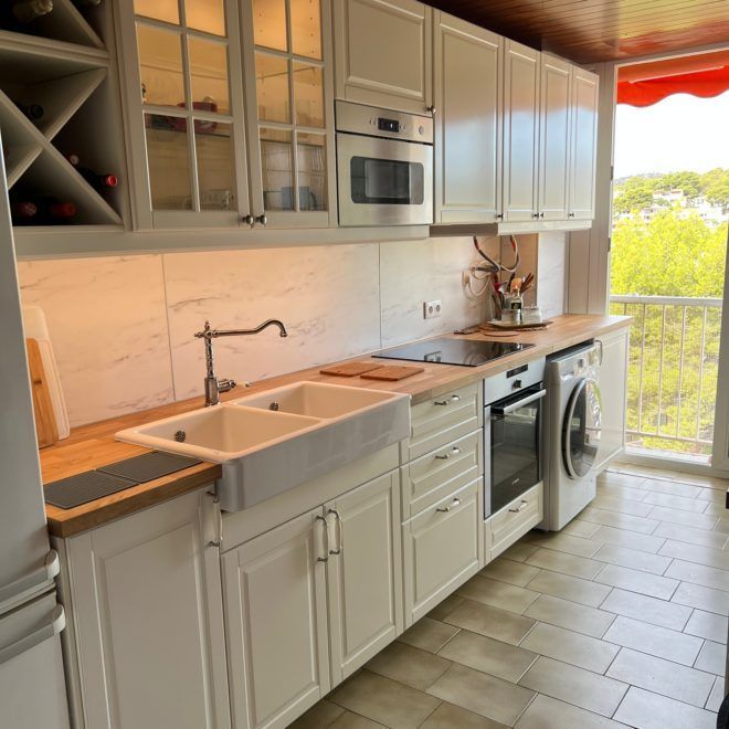 Una cocina con gabinetes blancos y electrodomésticos de acero inoxidable.