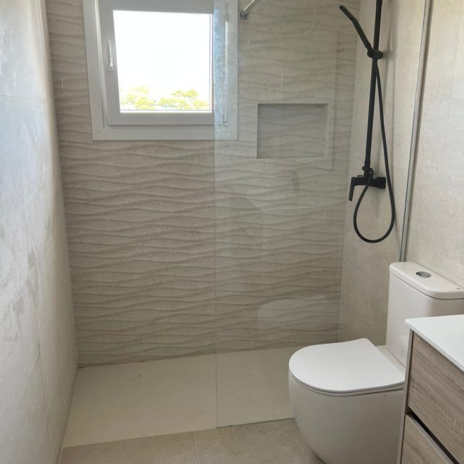 Un baño con inodoro, lavabo, ducha y ventana.