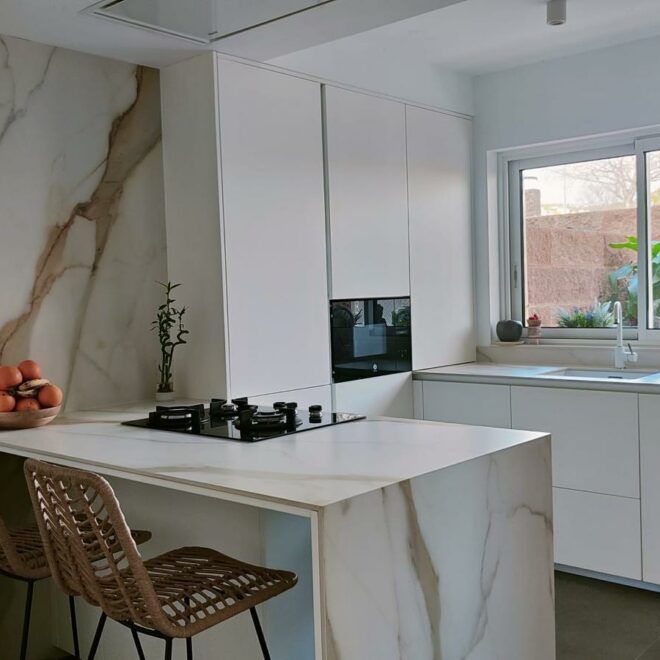 Una cocina con gabinetes blancos y una gran isla en el medio.