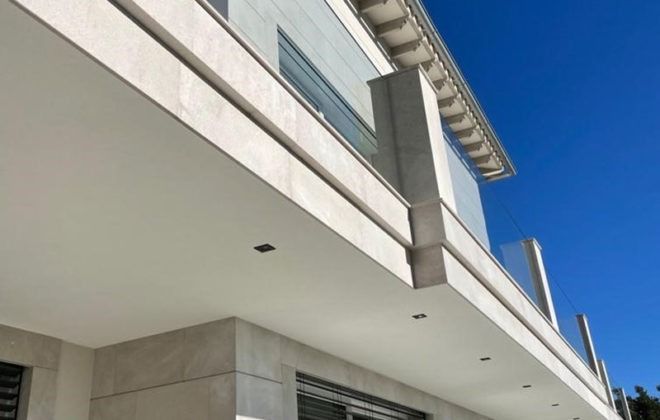 Un edificio con un balcón y un cielo azul al fondo.