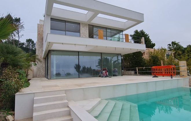 Una gran casa blanca con una piscina delante de ella.