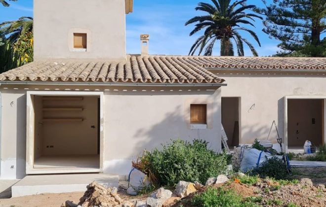 Una casa blanca con techo de tejas y una palmera al fondo.