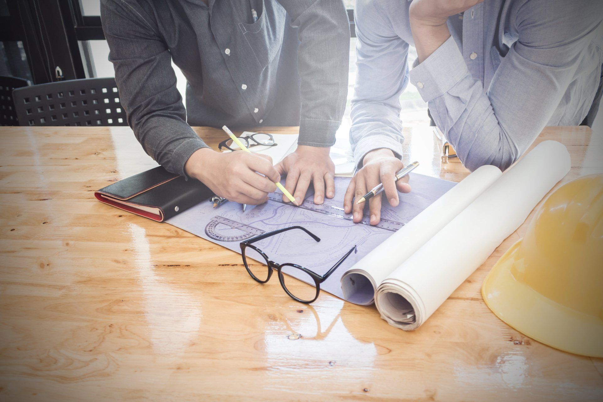 Deux hommes placent leurs mains sur des plans de construction