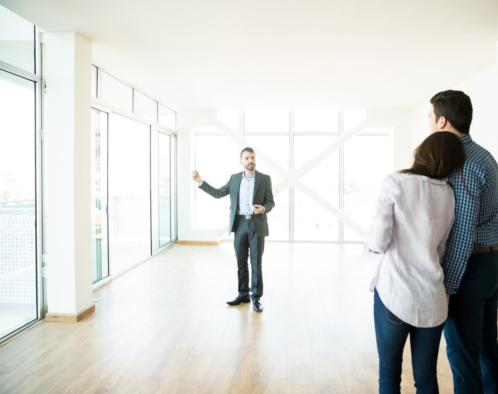 Homme parle à un jeune couple dans un appartement vide