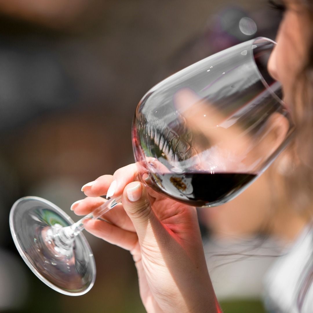 Una mujer está bebiendo una copa de vino tinto