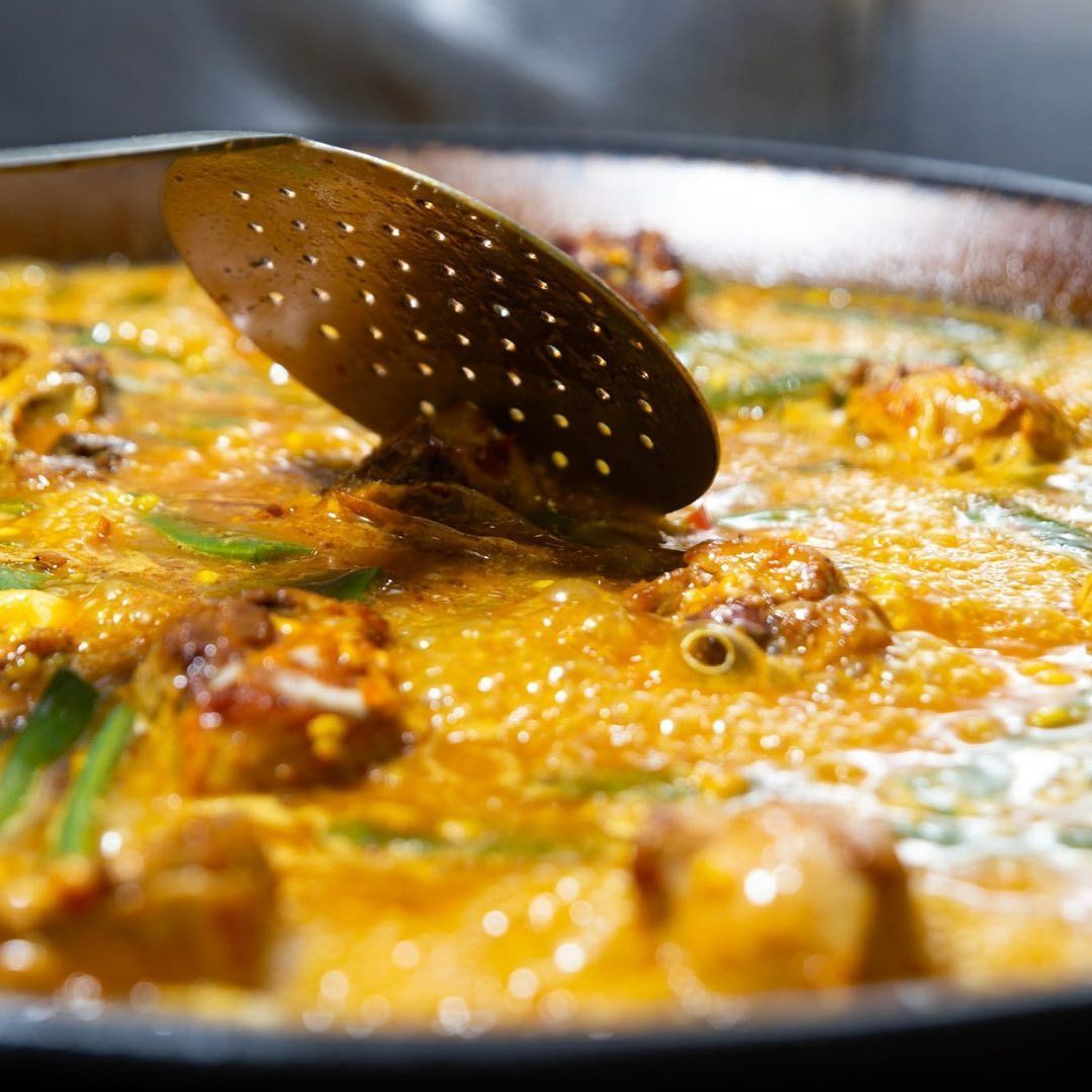 Un primer plano de una sartén con comida y una cuchara dentro.