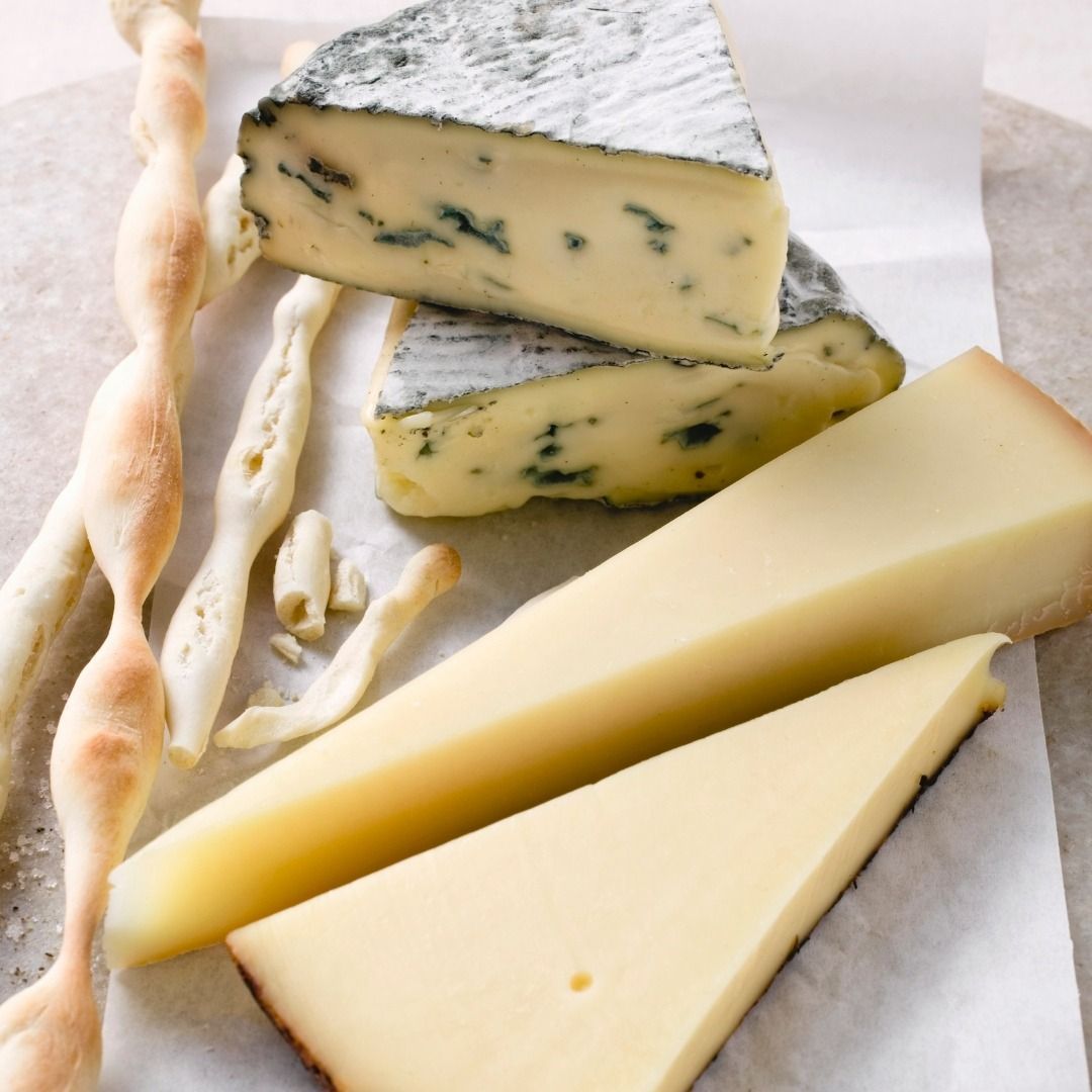 Una variedad de quesos y palitos de pan en una mesa.