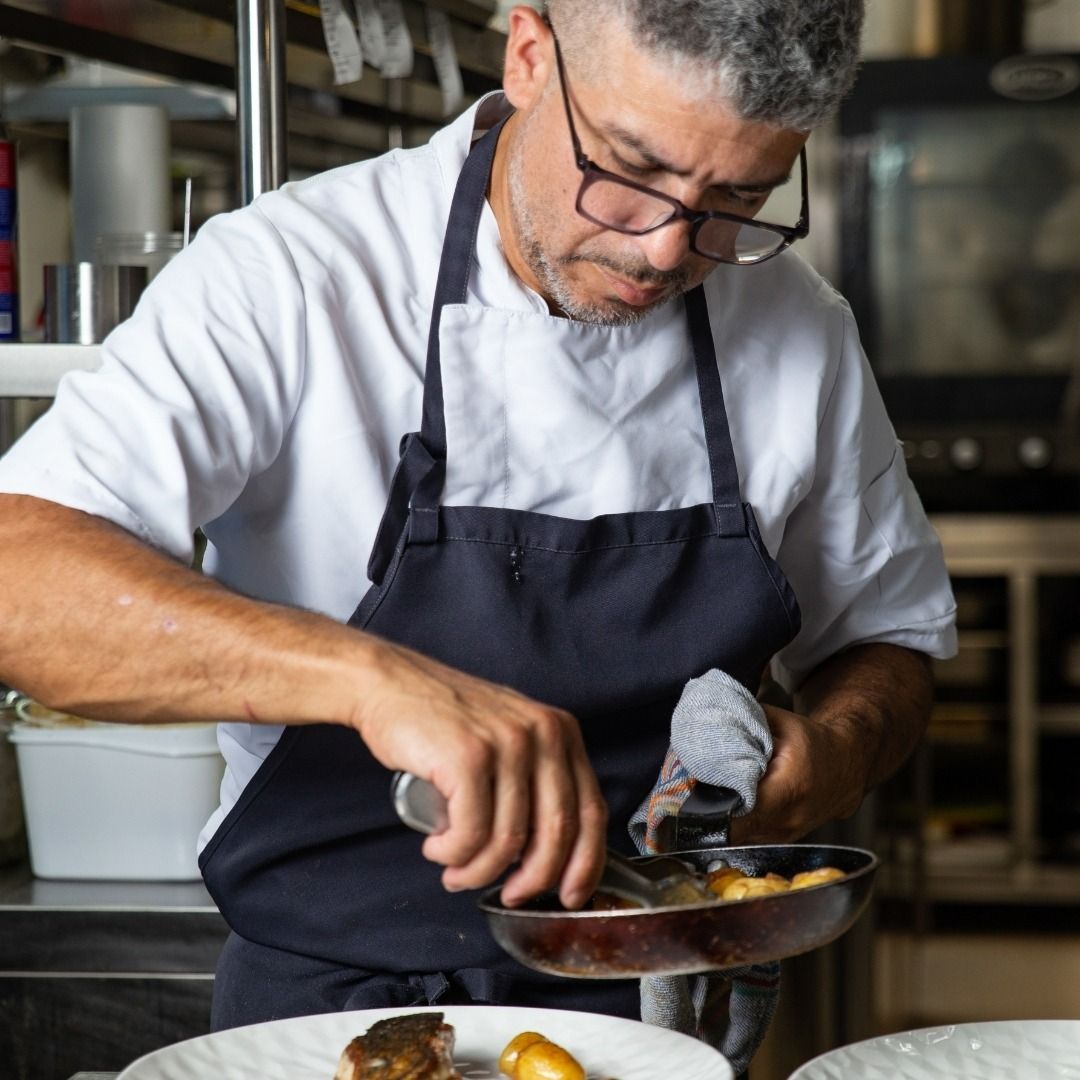 Un hombre con delantal está preparando comida en una cocina.