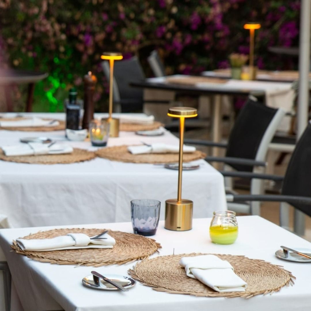 Una fila de mesas con velas y servilletas.