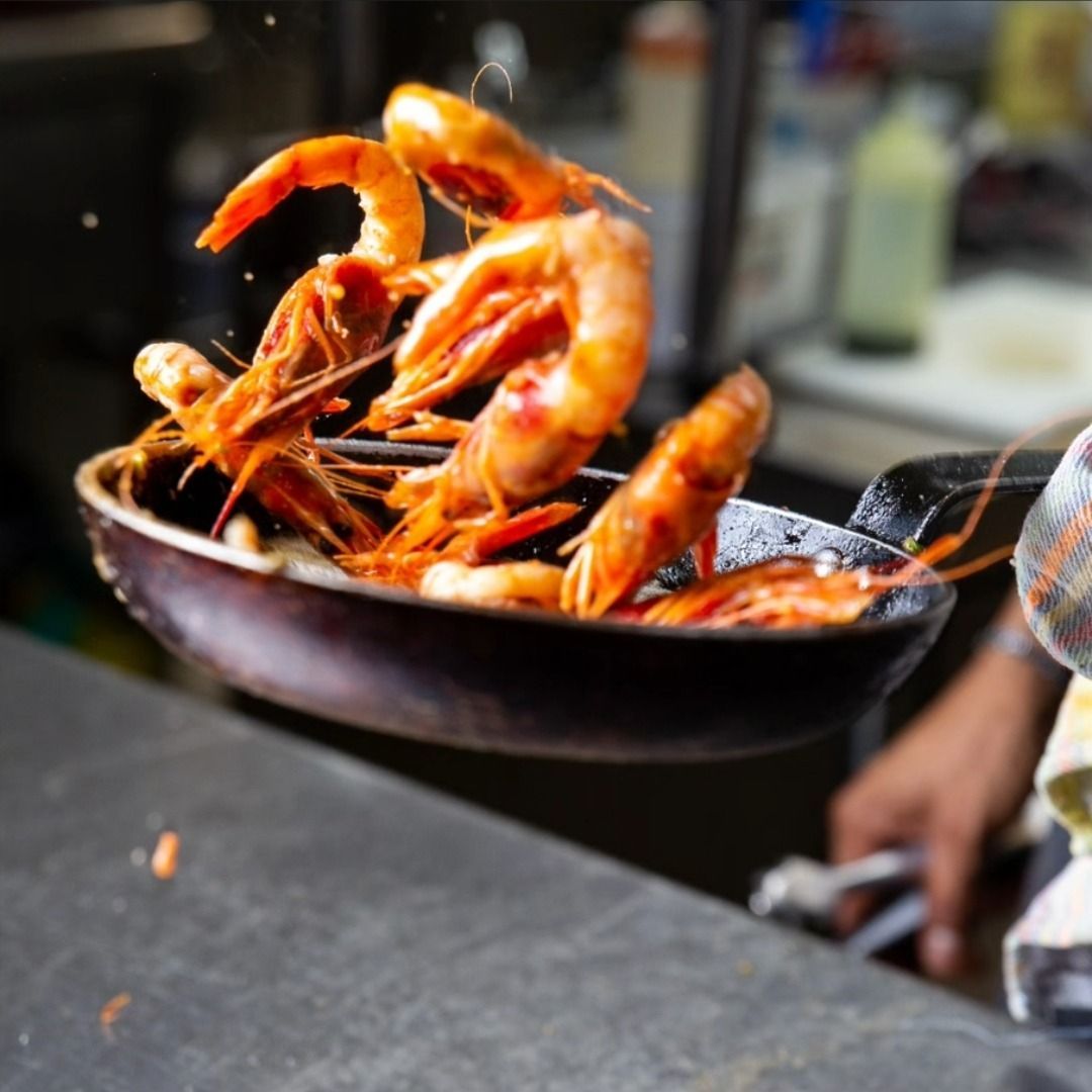 Una persona está cocinando camarones en una sartén.