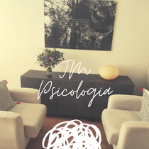 Consultorio de psicolog&iacute;a con dos sillones, un aparador, arte abstracto y un ramo de flores.