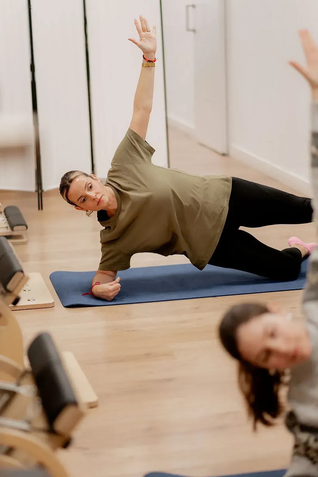 Una mujer está haciendo una plancha sobre una colchoneta de yoga en un gimnasio.