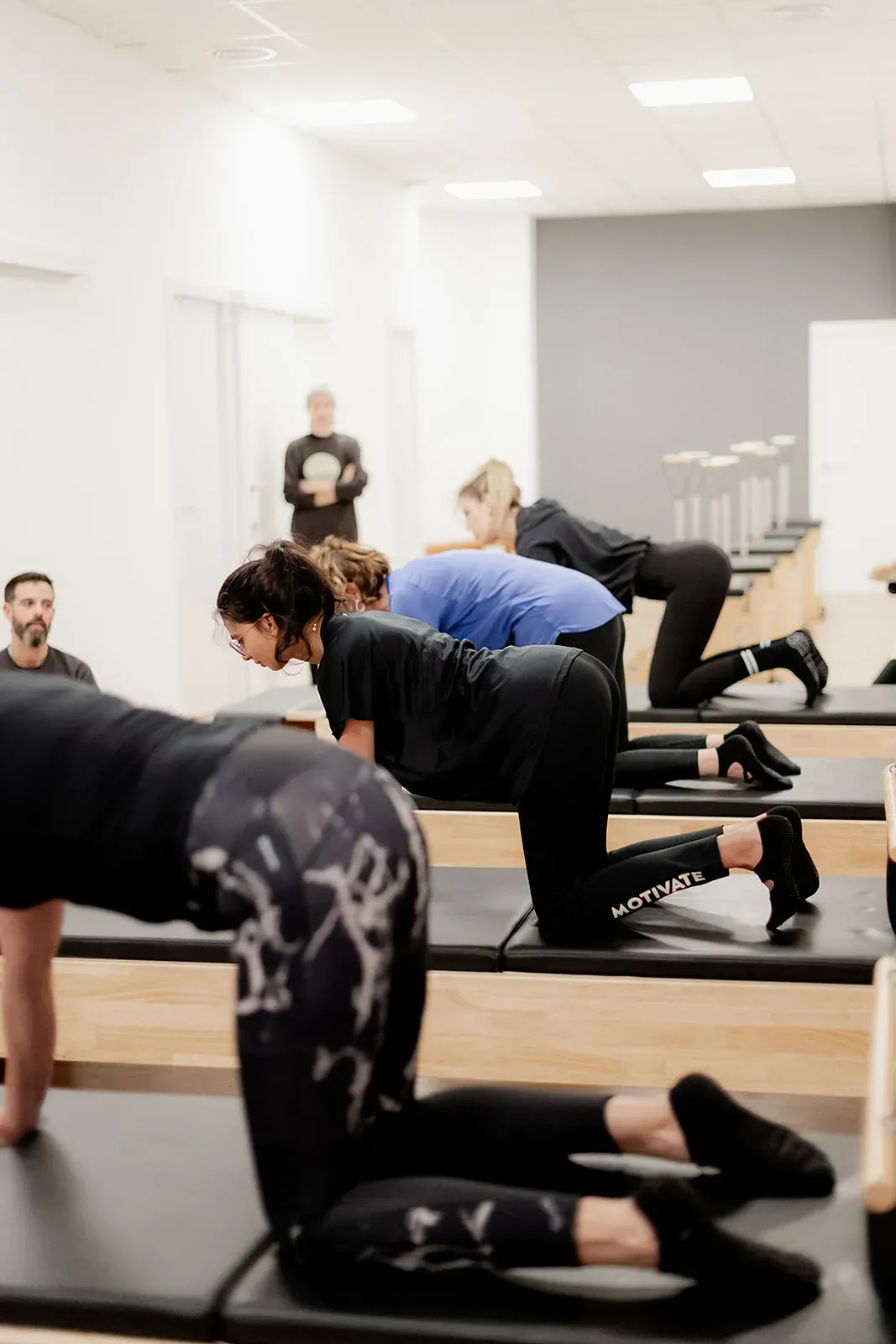 Un grupo de personas está haciendo ejercicios en mesas de pilates en un gimnasio.