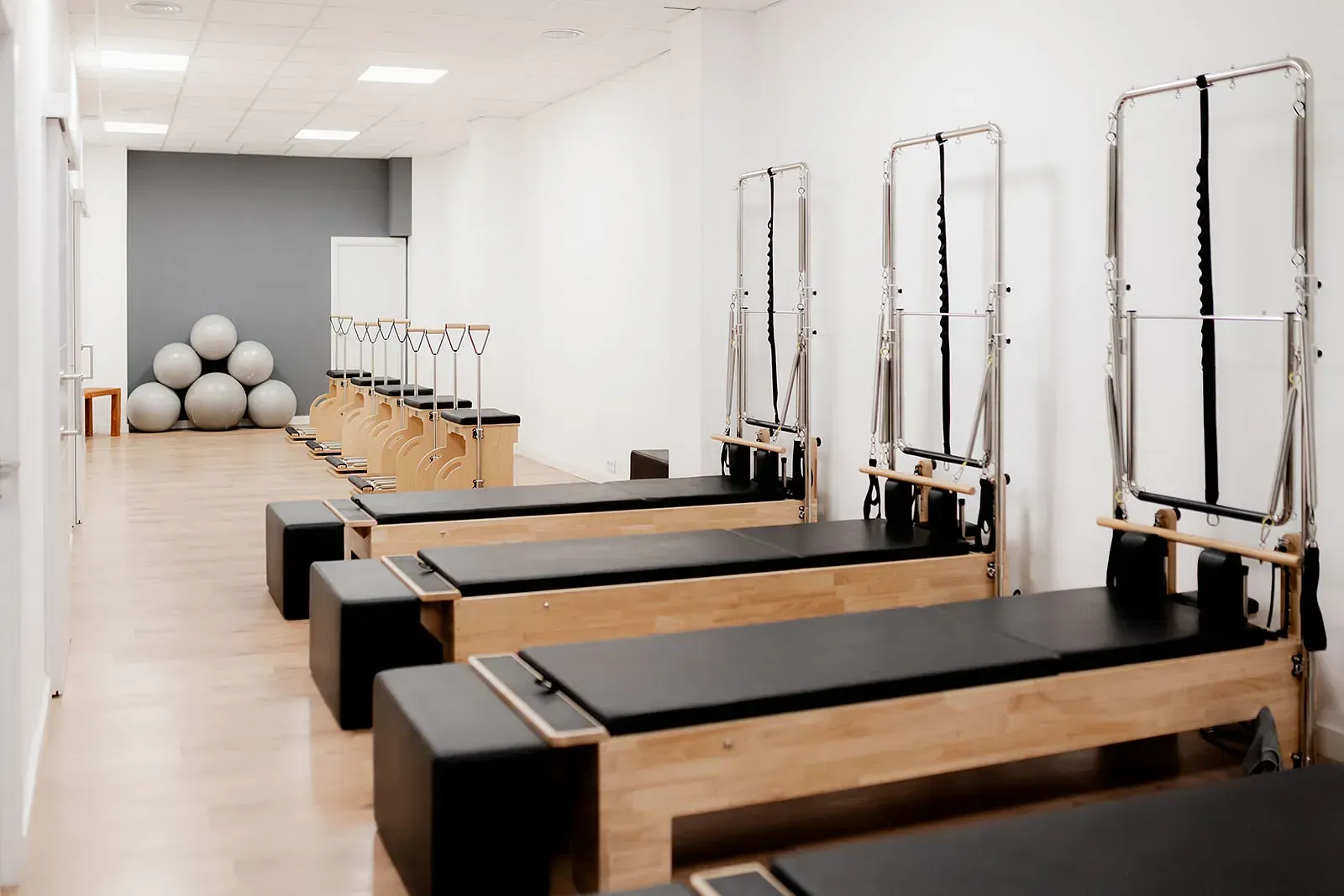 Una fila de mesas de pilates están alineadas en un gimnasio.