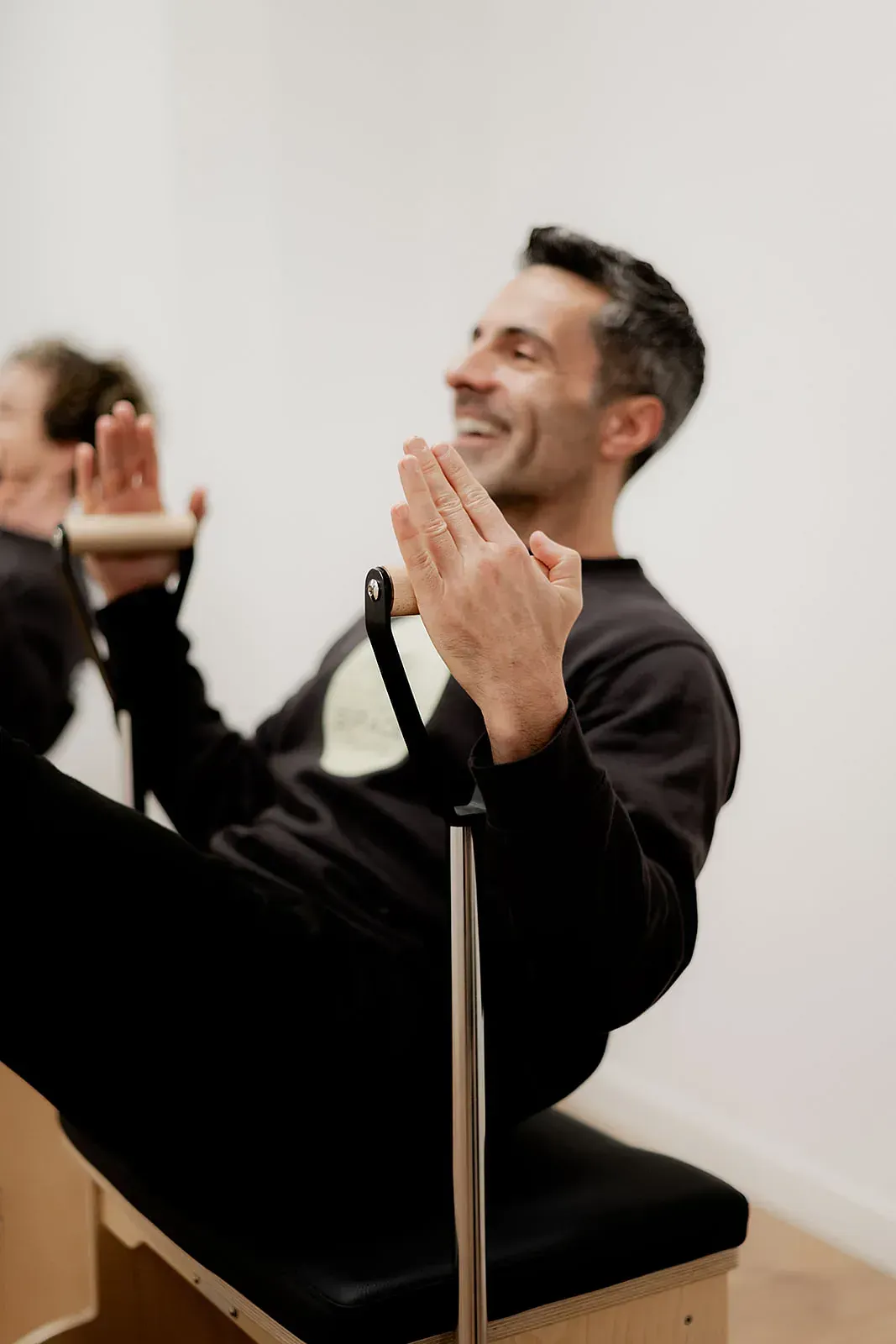 Un hombre está sentado en una silla con las piernas cruzadas y aplaudiendo.