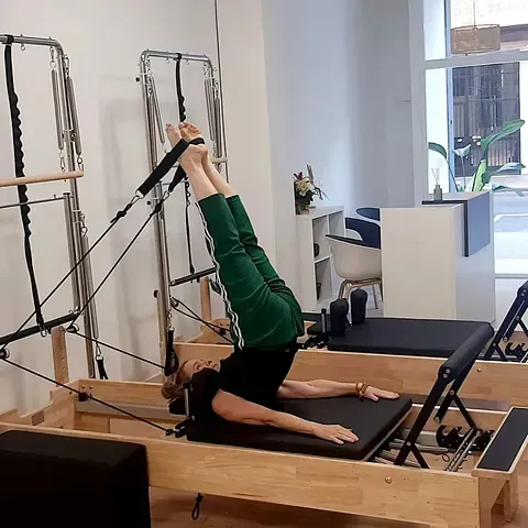 Una mujer está haciendo ejercicios en una máquina de pilates en un gimnasio.