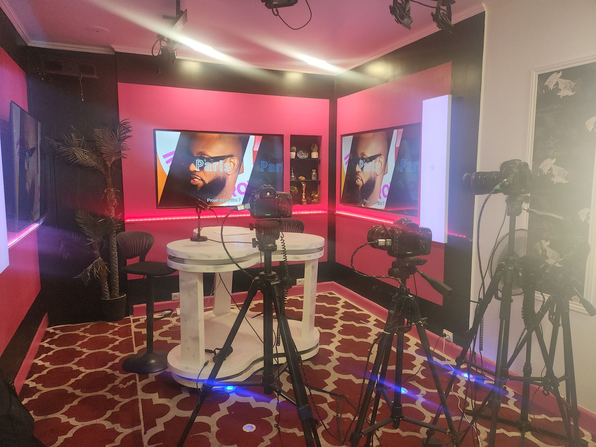 Une caméra filme un musicien jouant de la guitare en intérieur. L'écran de la caméra affiche le musicien.