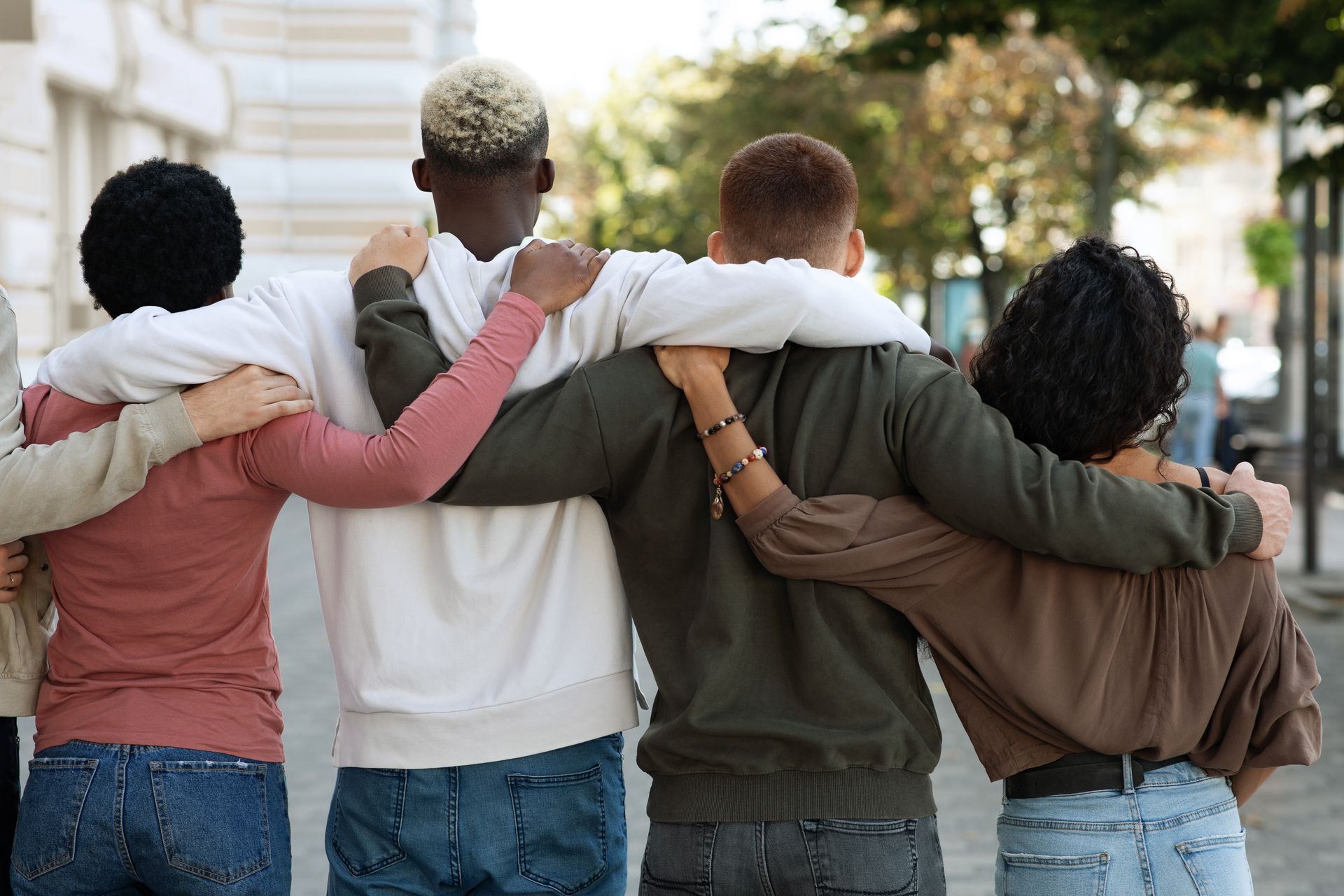 Un groupe de personnes, bras dessus bras dessous, marchant dans une rue.